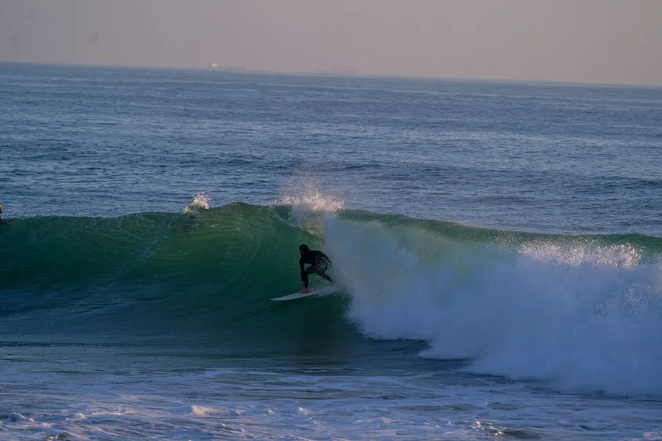 Surfer dropping into a green Atlantic barrel at sunrise
