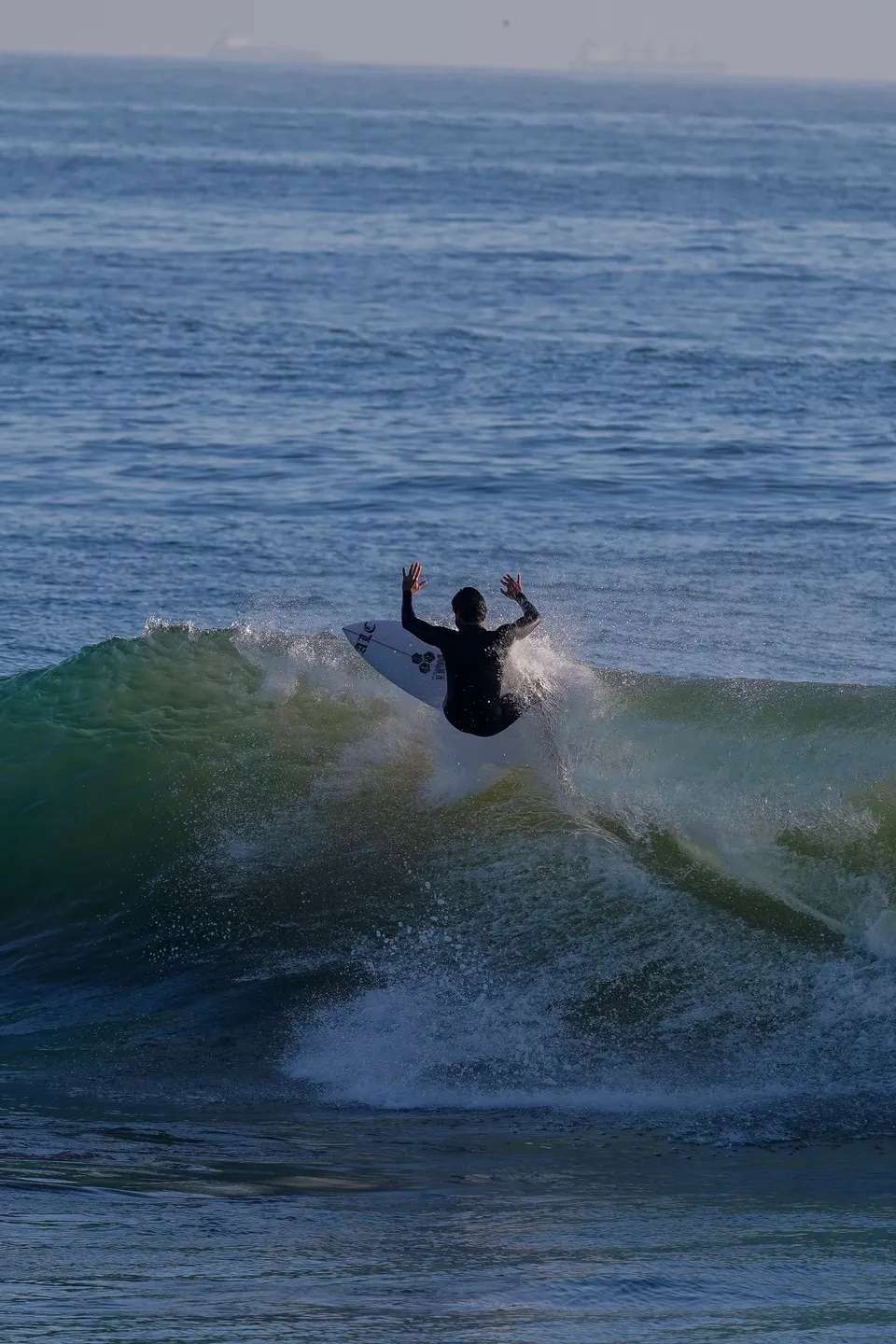 Surfer throwing heavy spray off the top lip in backlit afternoon light