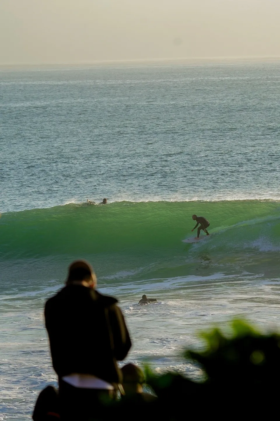 Surfer riding a glassy green wall at golden hour near Tamraght