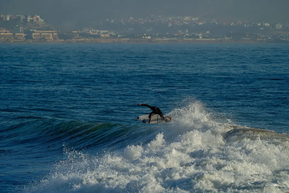 Surfer carving a hard turn with the Moroccan coast behind