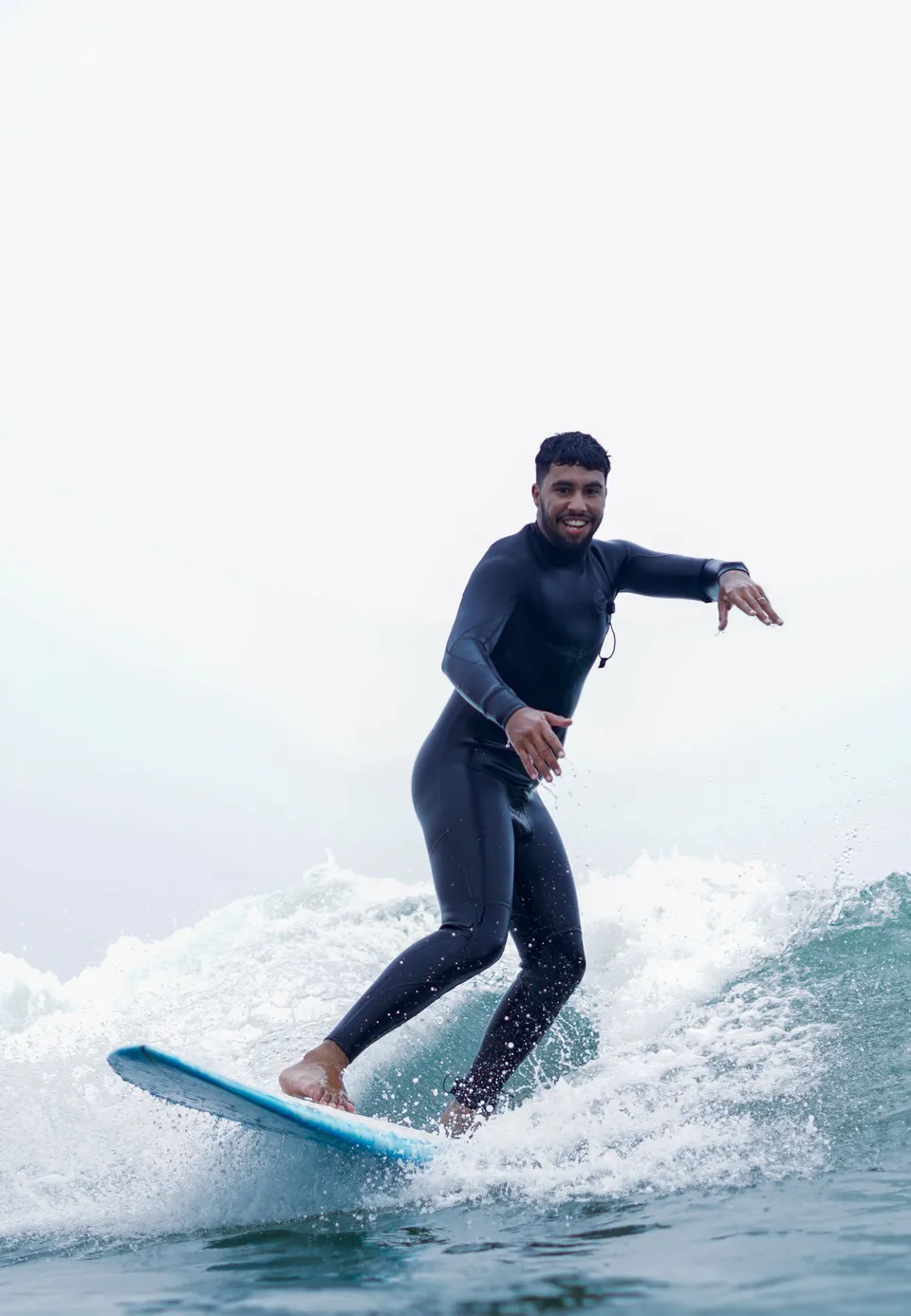 Smiling surfer riding a clean set wave in black wetsuit